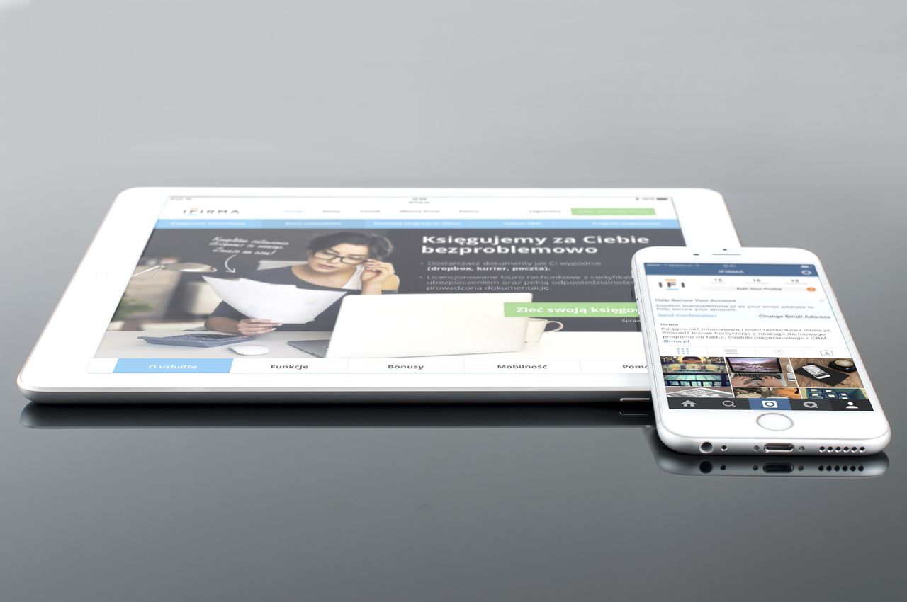 Une tablette moderne et un smartphone affichant du contenu web sur une surface réfléchissante, mettant en avant la technologie et la connectivité.